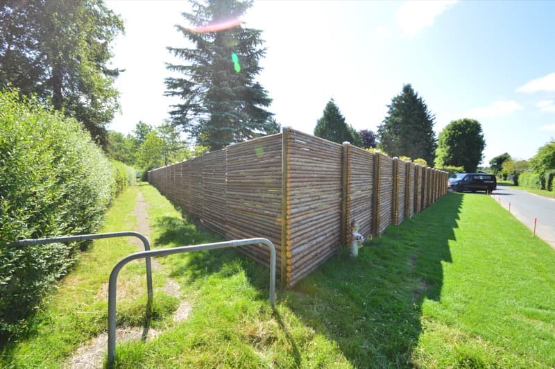 Lang række trykimprægneret raftehegn langs vej